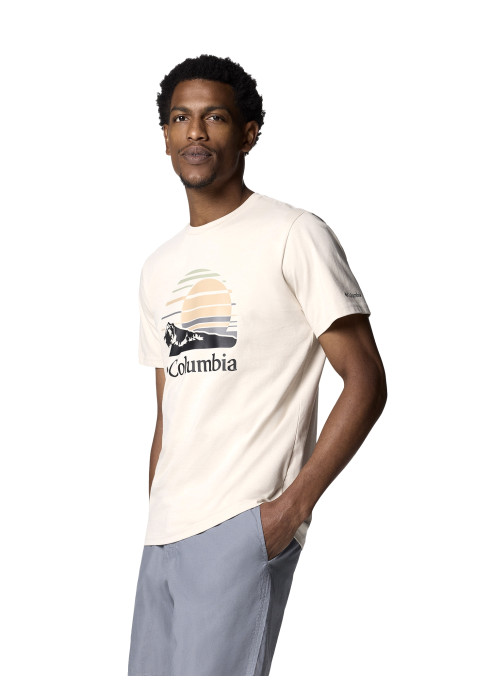 Чоловік у світло-бежевій футболці Columbia Path Lake Graphic Tee II та сірих шортах напівповерхом на білому тлі