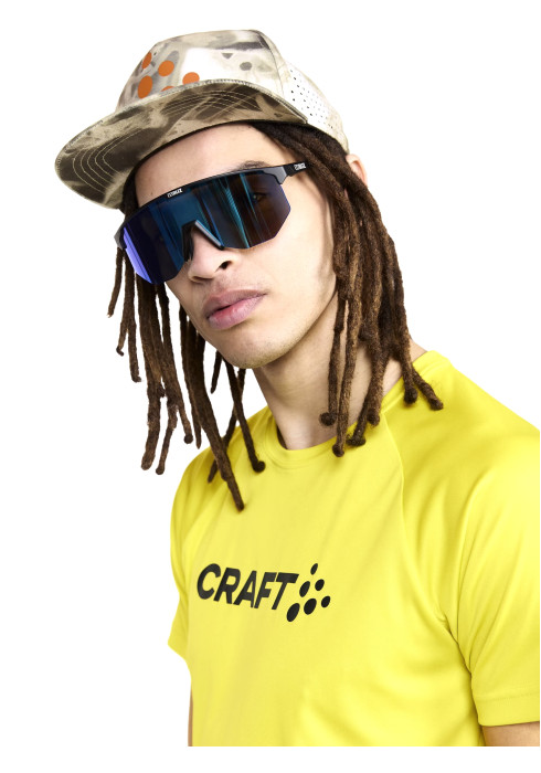 Чоловік у яскраво-жовтій спортивній футболці CRAFT Core Essence Logo Tee, сонцезахисних окулярах та кепці зблизька