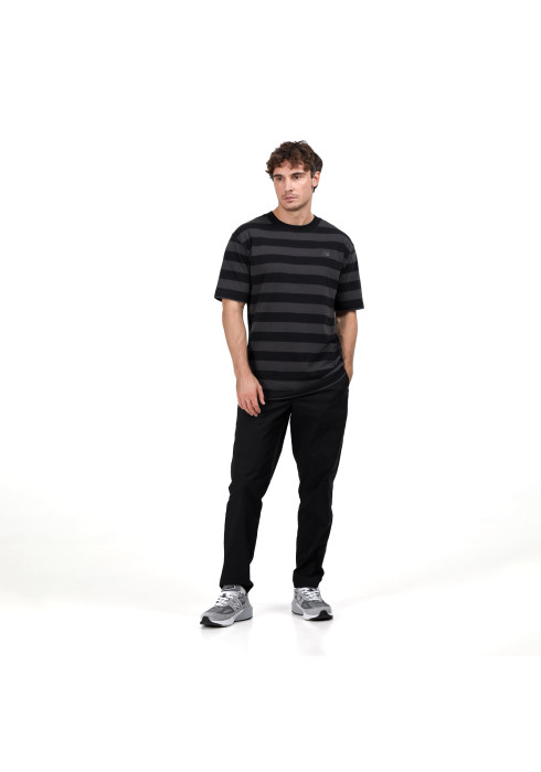 Чоловік у повний зріст у чорно-сірій смугастій футболці New Balance Athletics Cotton Thick Stripe, штанах і кросівках спереду на білому тлі
