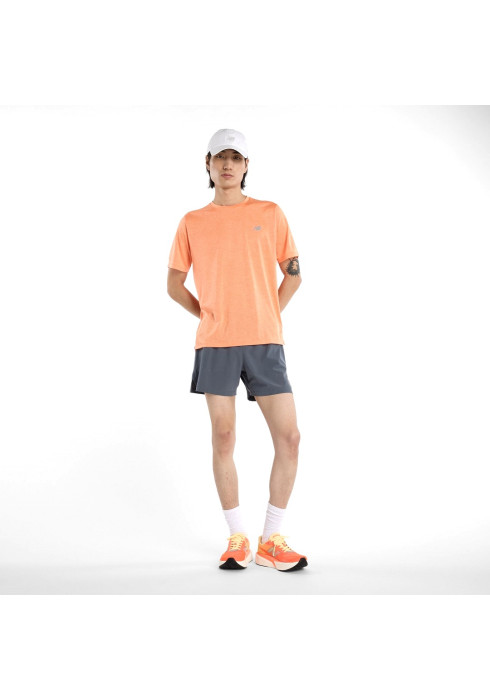 Чоловік у повний зріст у помаранчевій спортивній футболці New Balance Athletics Prfm, сірих шортах та білій кепці на білому тлі