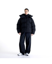 Дівчина у чорній пуховій куртці New Balance Premium Puffer та широких штанах у повний зріст