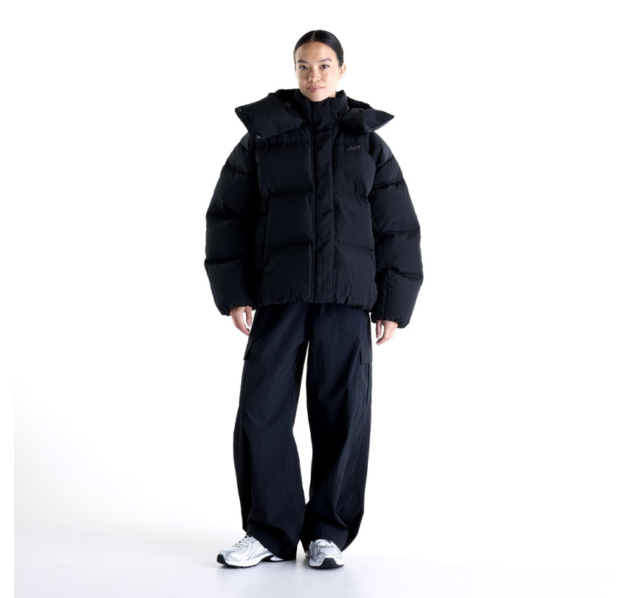 Дівчина у чорній пуховій куртці New Balance Premium Puffer та широких штанах у повний зріст