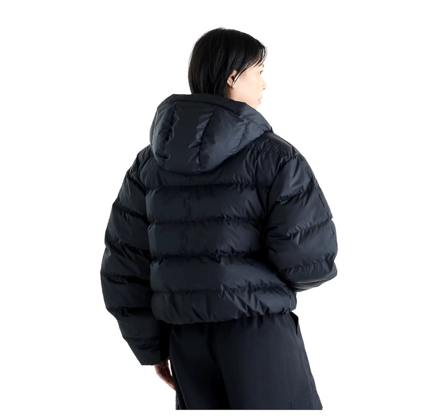 Вигляд ззаду у повний зріст на жіночий чорний пуховик New Balance NB Boston Puffer з об'ємним капюшоном на моделі