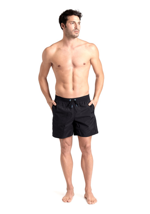 Чоловік у повний зріст у чорних шортах Arena Beach Boxer Solid з руками в кишенях на білому тлі
