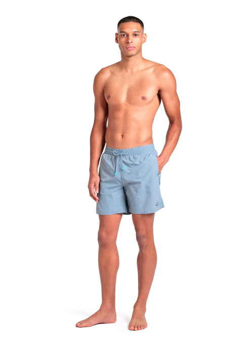 Чоловік у повний зріст у сіро-блакитних шортах Arena Beach Boxer Solid з рукою в кишені на білому тлі