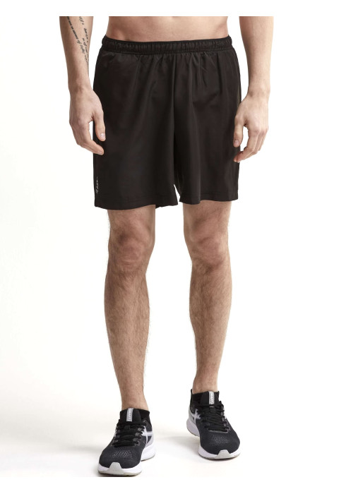 Чоловік у чорних тренувальних шортах Craft Eaze Woven Shorts та кросівках студійний вигляд спереду на білому тлі