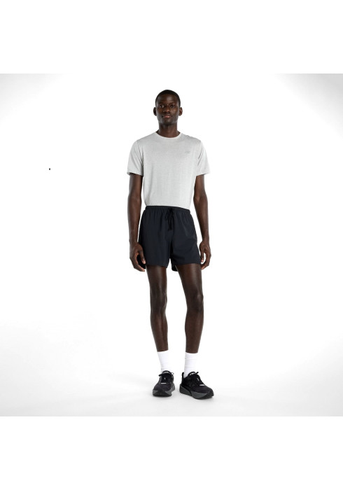 Чоловік у чорних спортивних шортах New Balance Run Essentials 5 та сірій футболці у повний зріст