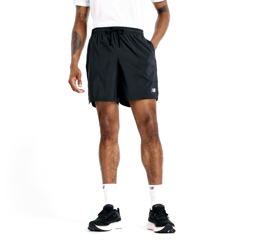 Чоловік у чорних спортивних шортах NB Sport Short 7" та білій футболці, вигляд спереду, фірмовий білий логотип на лівому стегні