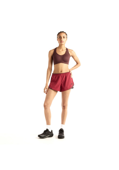 Дівчина у бордовому спортивному топ-бра та бігових шортах New Balance RC Essentials Short 3'' у повний зріст