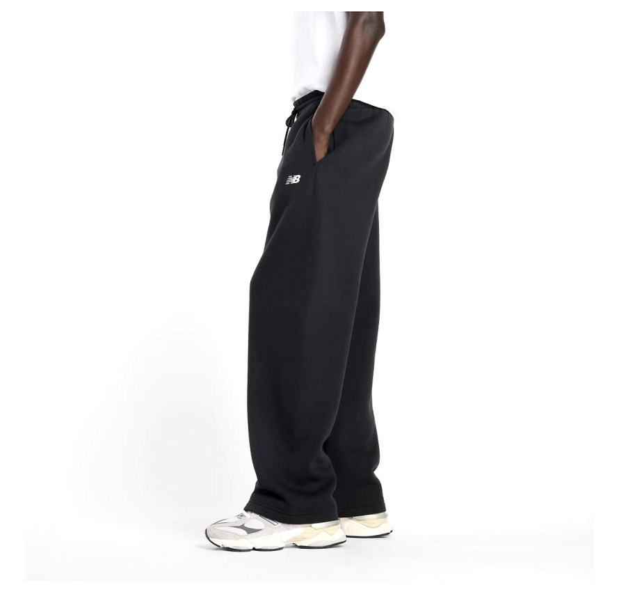 Чоловік у чорних спортивних штанях New Balance Sport Essentials студійний вигляд збоку на білому тлі