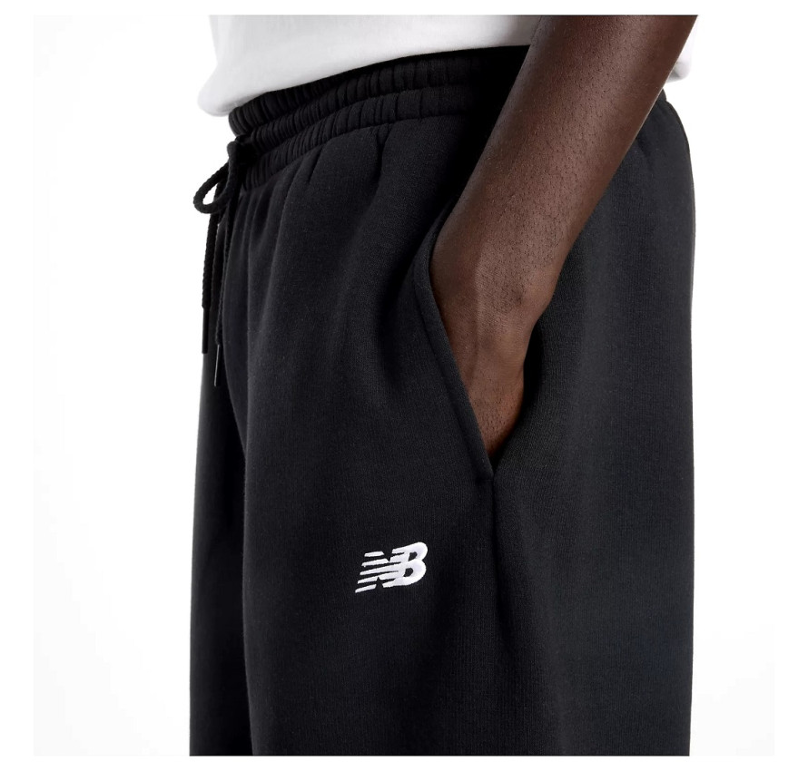 Крупний план фірмового вишитого білого логотипа New Balance на чорній тканині біля кишені зблизька