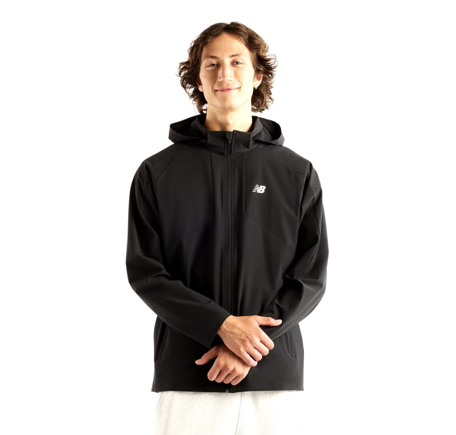Чоловік у чорній вітрівці New Balance Utility Stretch Woven з піднятим капюшоном, вигляд спереду